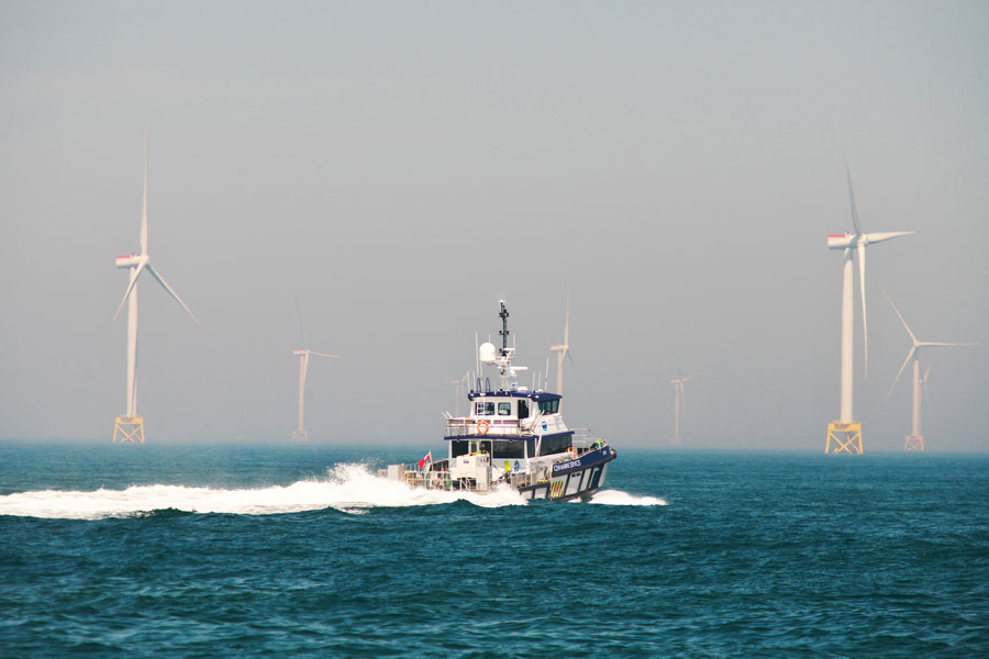 Marine vessel sails into a windfarm on the horizon