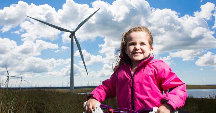 Photo of a girl standing in front of a wind turbine